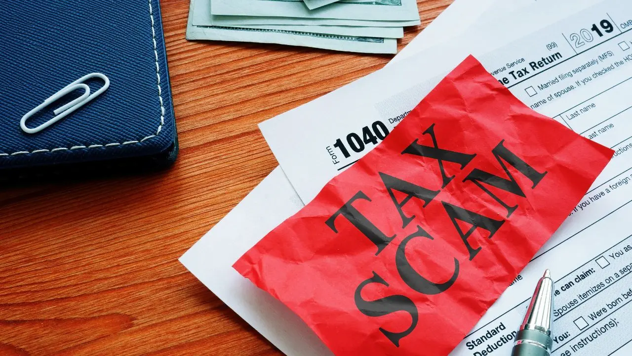Pile of 1040 papers on a desk with the the words tax scam in red